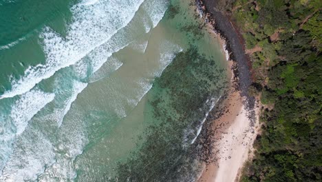 waves splashing on the shore at fingal head beach in new south wales, australia - aerial top down