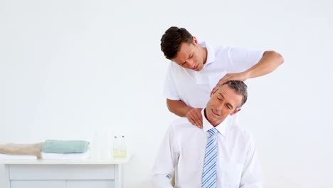 Physiotherapist-giving-stressed-businessman-a-neck-massage