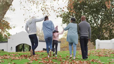 Video-of-rear-view-of-african-american-parents-and-grandparents-and-granddaughter-walking-in-garden