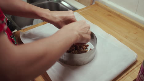la mujer pone la mezcla vegetariana de frutas y nueces en una bandeja para hornear circular