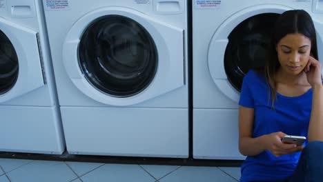 Woman-talking-on-mobile-phone-at-laundromat-4k