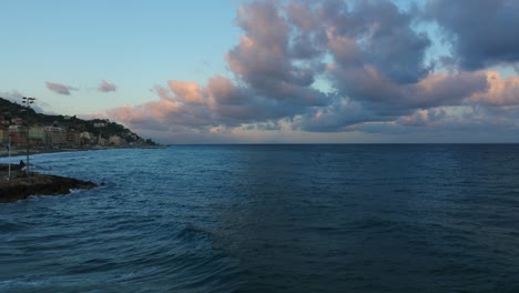 Flying-toward-open-sea-from-Varazze-in-Liguria-region-at-sunset,-Italy