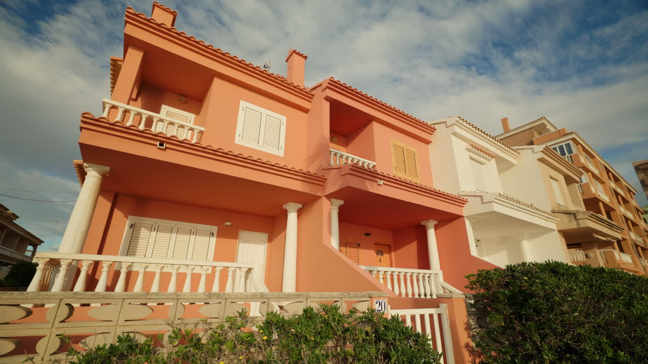 Exterior view of a two-story orange house with white windows and balcony