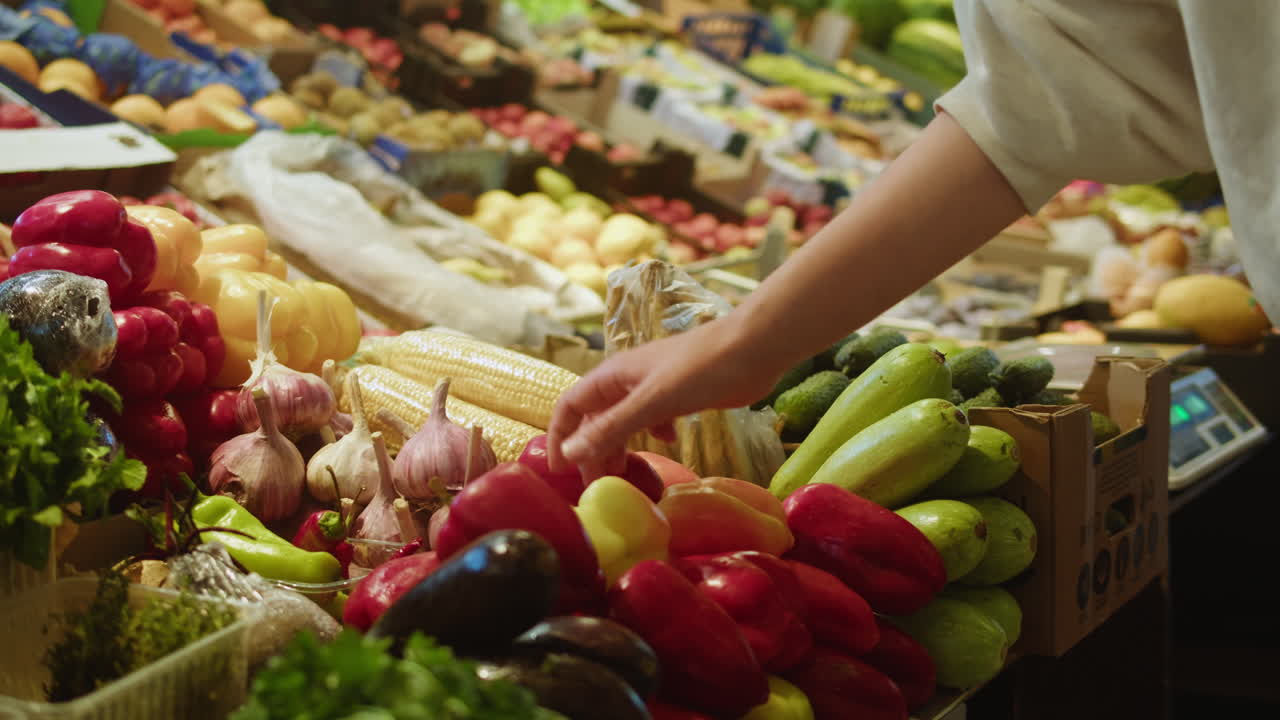 Hand Selecting Fresh Vegetables at a Vibrant Farmer's Market Stall