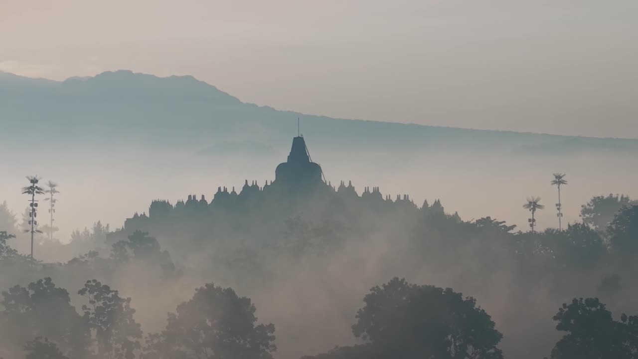 Suggestiva nebbia mattutina intorno al Tempio di Borobudur, panoramico paesaggio indonesiano con iconica struttura antica.