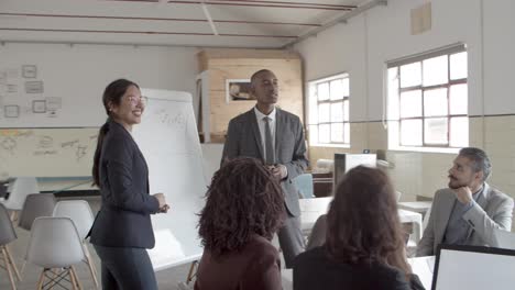 Smiling-speakers-talking-and-pointing-at-whiteboard