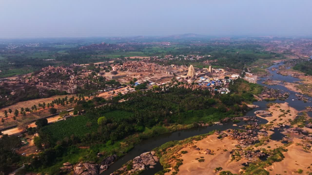 Vista aerea della vegetazione di Vijayanagara con il fiume Tungabhadra e il tempio Virupaksha ad Hampi, Karnataka, India. Di giorno, ripresa in carrello, ripresa con drone, 4K