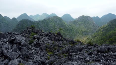 Aerial-dolly-over-rock-formations-into-green-valley-of-mountains-and-trees