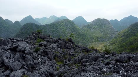aerial dolly over rock formations into green valley of mountains and trees
