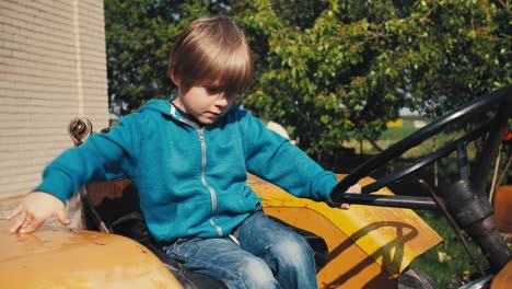 Boy-on-the-old-yellow-tractor,-pretending-to-be-driving