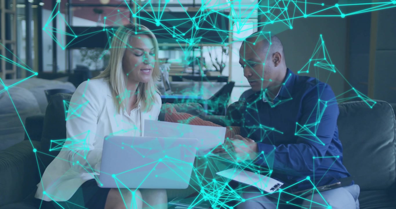 Gazing at laptop, woman collaborating with man in office reviewing business report using tablet