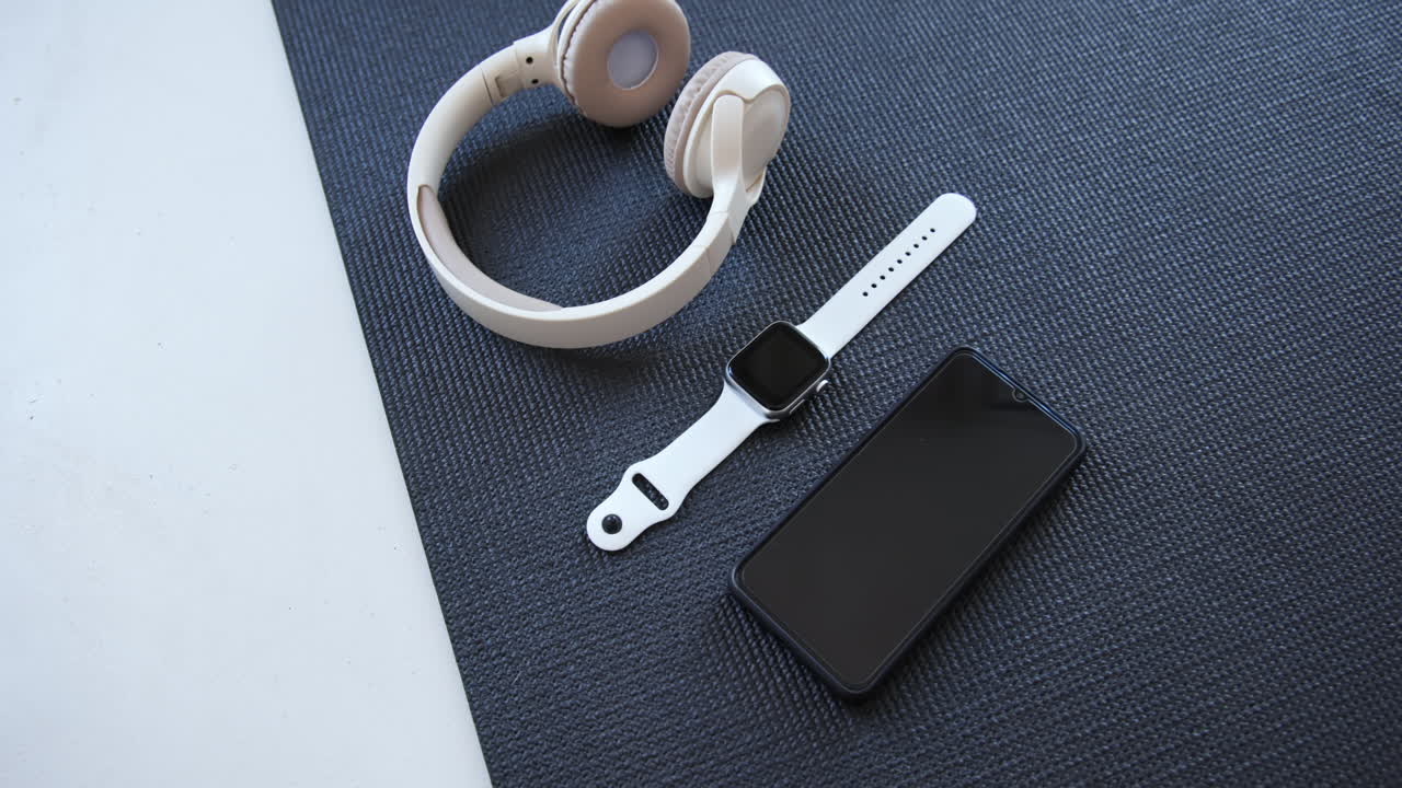 On yoga mat, headphones, smartwatch, smartphone arranged for workout session, at home, copy space