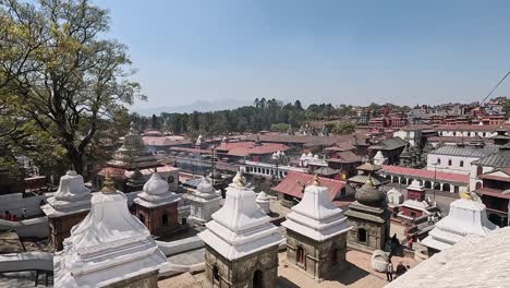 pashupatinath temple cremation complex on the banks of sacred bagmati river in kathmandu, nepal. overlooking white mausoleums, roofs of pandra shivalaya