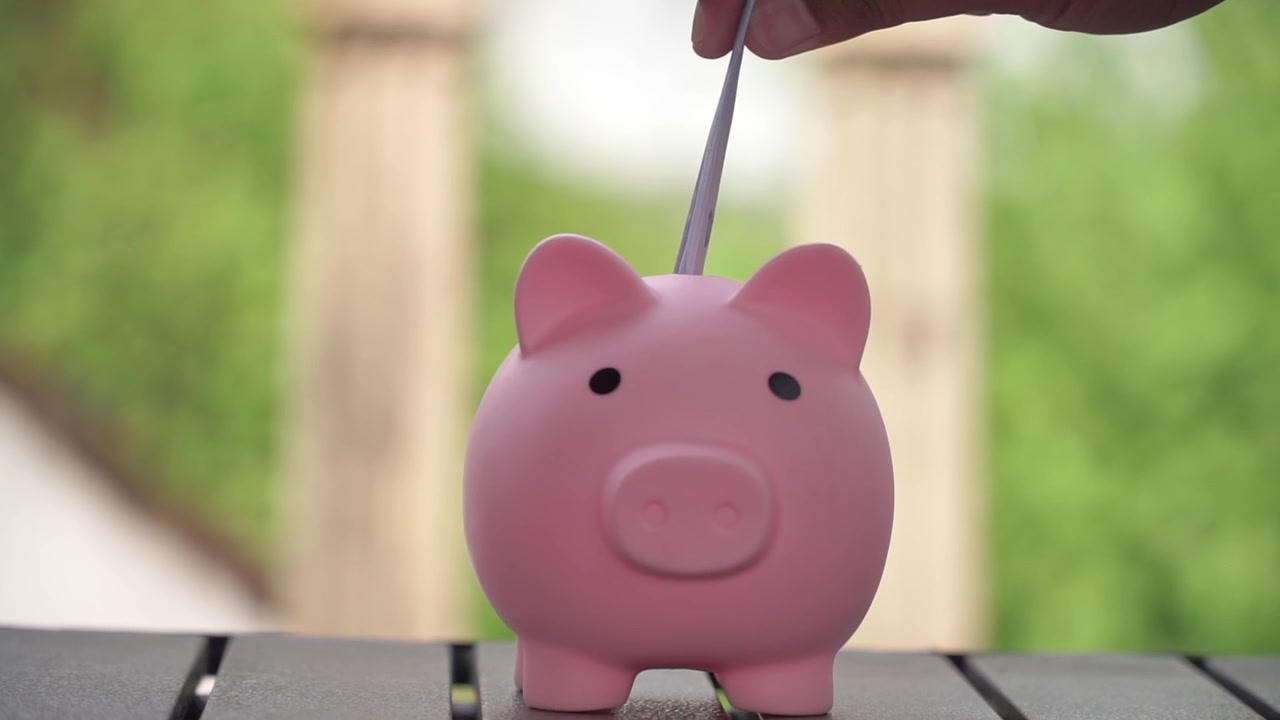 Hand saving coins into piggy bank, symbol of banking, investment and money management. financial planning and smart saving strategy concept.