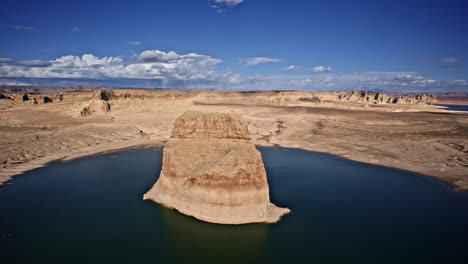 drone gliding above lake powell, showcasing a towering rock formation amidst the vast desert canyon scenery.
