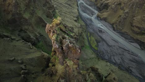 a dramatic rock formation rises above a winding river in a deep icelandic canyon, showcasing the rugged and remote wilderness of northern iceland.