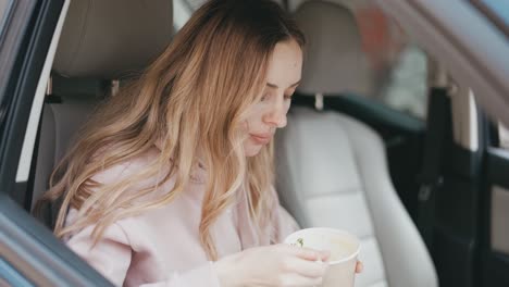 woman eating soup inside the parked car