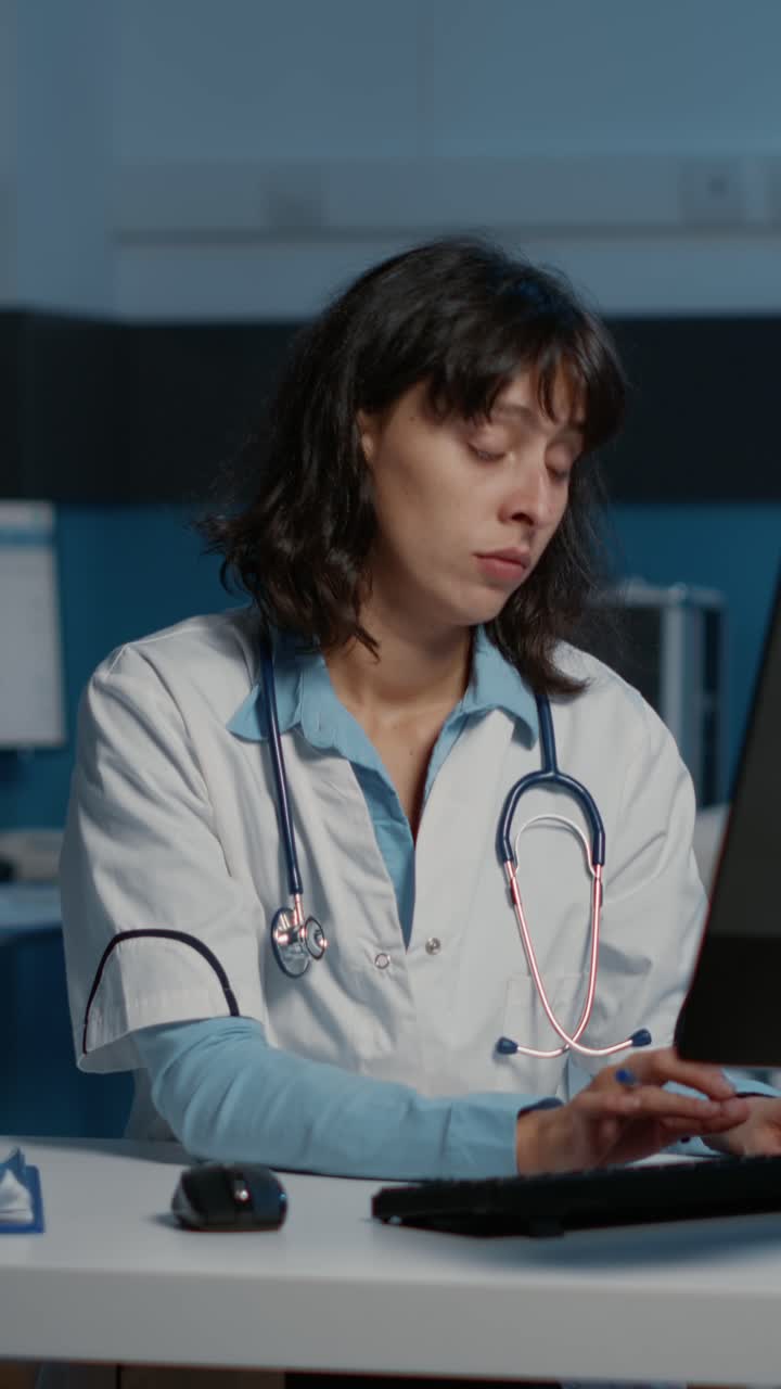 Vertical video: Tired exhausted physician woman working late at night in hospital office