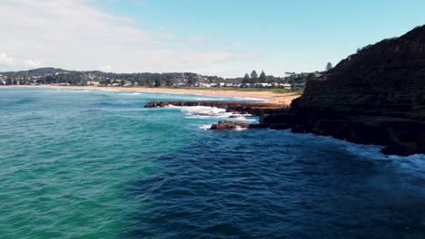 Drone-aerial-pan-scenic-shot-of-North-Avoca-beach-coastline-headland-with-point-Central-Coast-tourism-Pacific-Ocean-NSW-Australia-4K