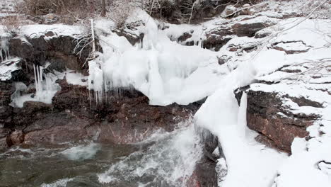 clima invernal que sopla nieve sobre formaciones rocosas heladas