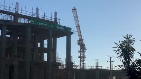 crane moving behind construction building, in piassa