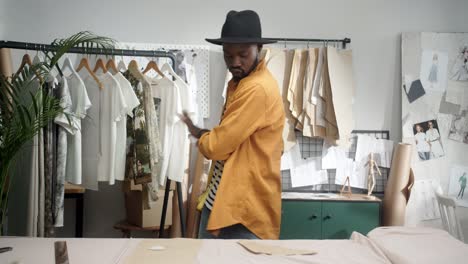 cheerful young designer drawing an outline on the cloth and dancing in studio 2