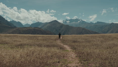 hombre de amplio ángulo levantando los brazos en el paisaje andino