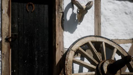 old wood wheel and black door at white house