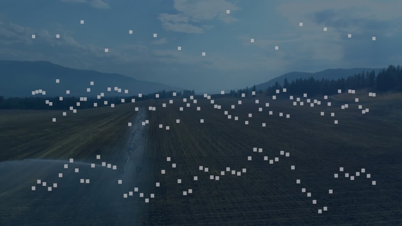 部分的に曇った青空の下、センターピボット灌漑パイプラインが作物の列に水をアーチ状に散布している