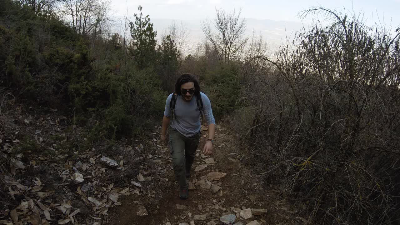 hombre caminando hacia la cámara, en una pista de montaña en el bosque