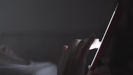 woman taps on mobile phone screen in dark room close view