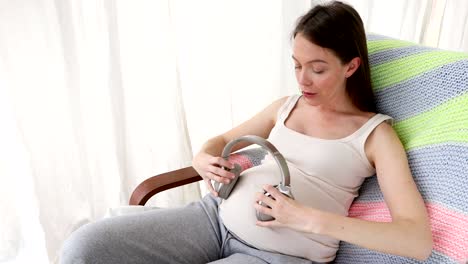 happy pregnant woman listening to music with baby
