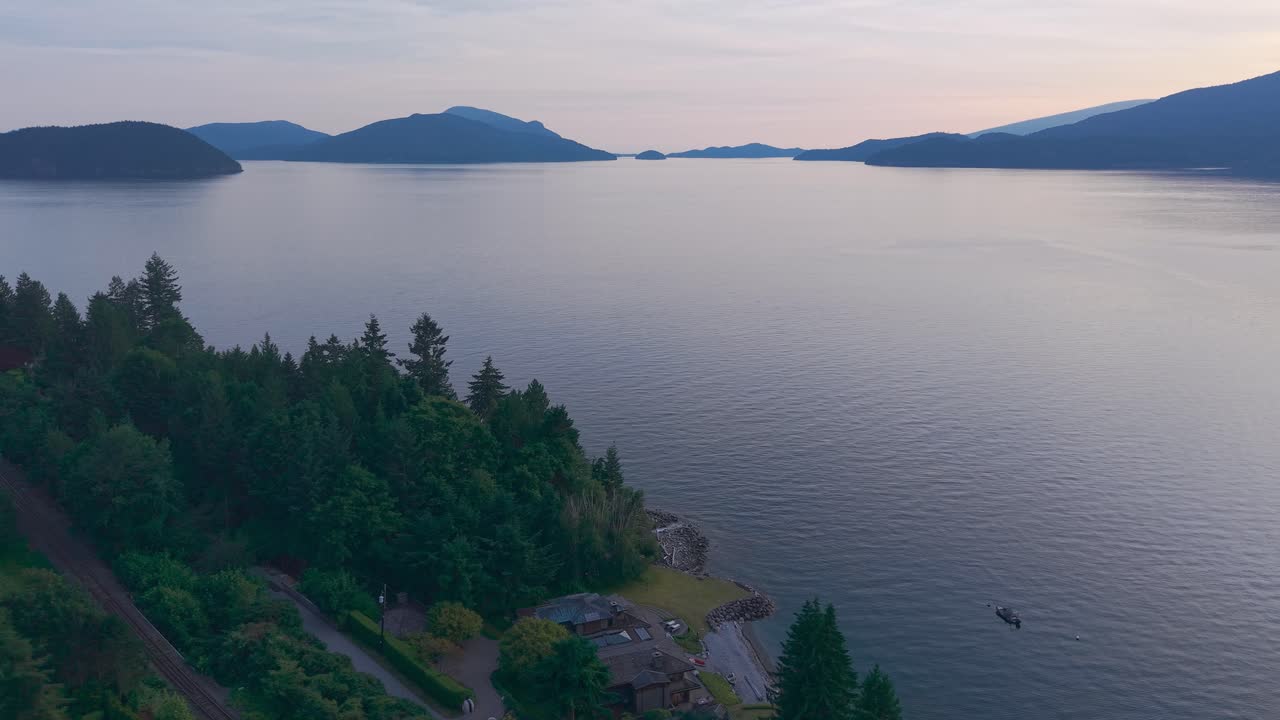An Aerial drone shot from Lions Bay, British Columbia, Canada featuring Bowen Island and Bowyer Island on the horizon at sunset
