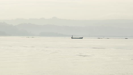 fisherman standing on boat floating in obidos lagoon in portugal