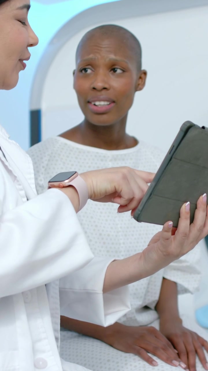 Vertical video: Showing Dr tapping tablet in clinic explaining results while patient asking, gown