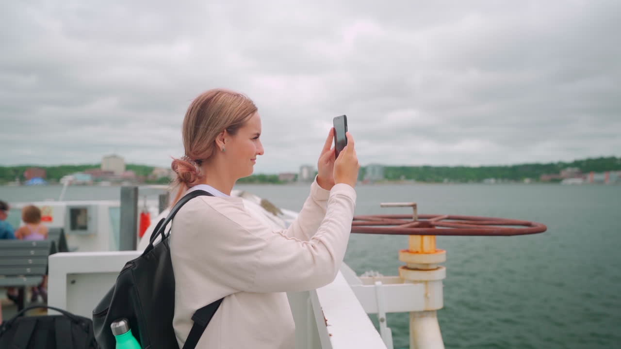 mujer con cabello rosado en la costa del este de canadá tomando un teléfono en su celular durante el mediodía