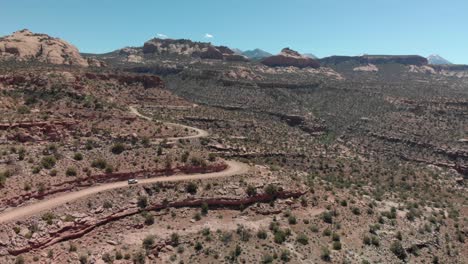 Aerial-dolly-tracks-SUV-vehicle-driving-on-gravel-road-in-Utah-canyon