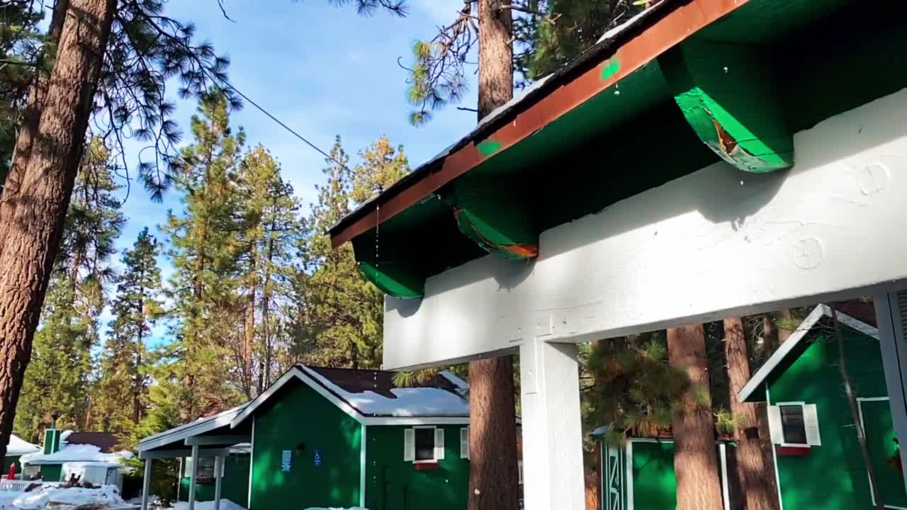 toma amplia en cámara lenta de gotas de agua que gotean de la línea del techo debido al derretimiento de la nieve