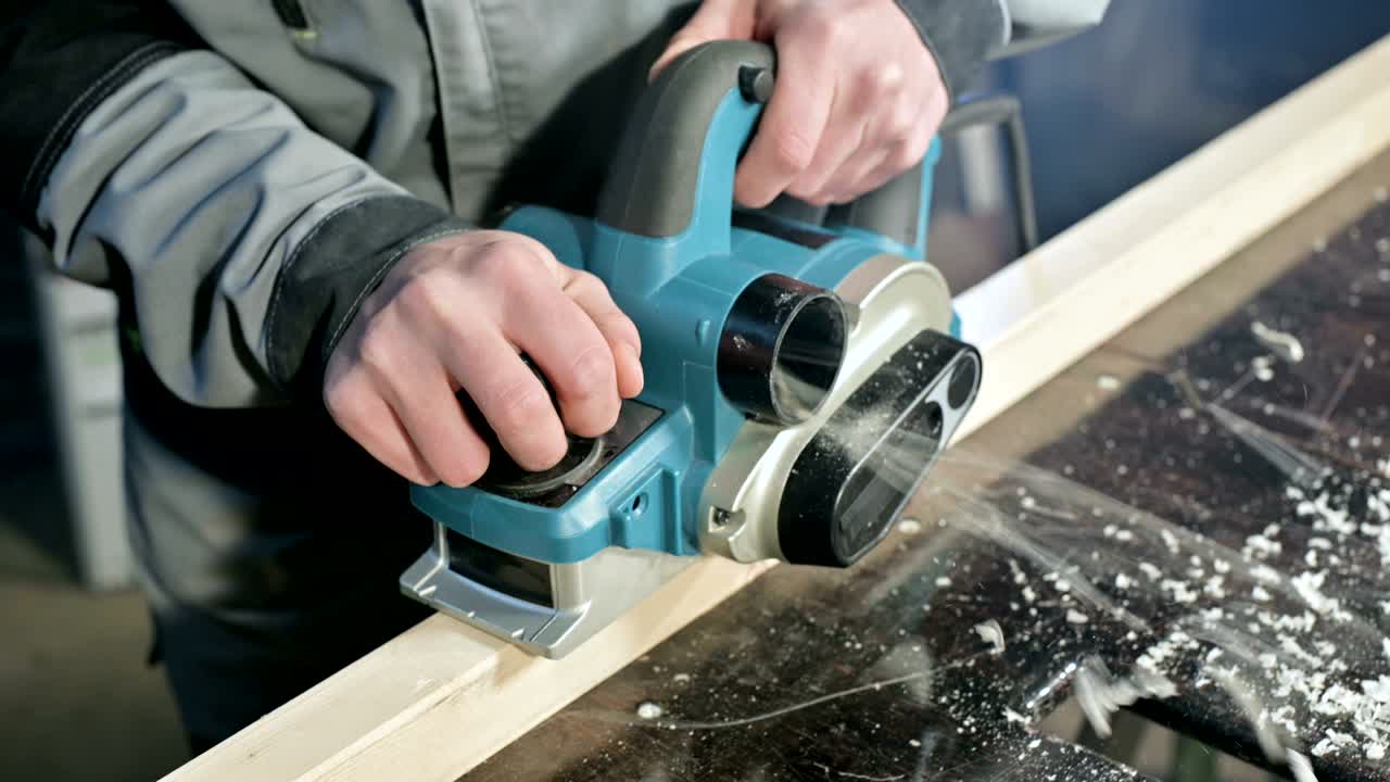 крупный план руки плотника, работающего с электрическим самолетом в домашней мастерской