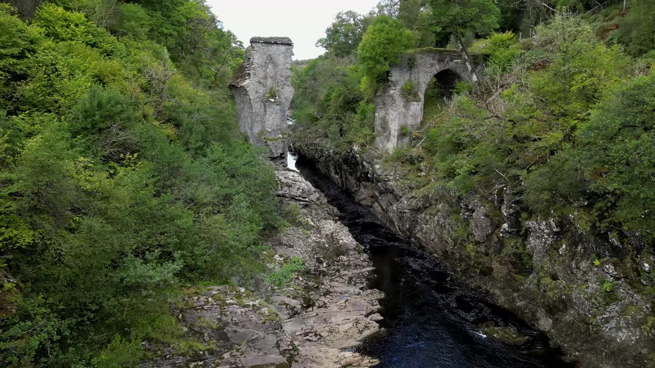 Um drone segue o rio corrente acima, passando por pilares de ponte de pedra em ruínas na zona rural da Escócia