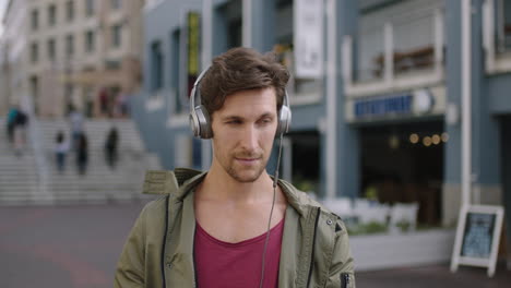 portrait of young attractive caucasian man in busy urban street using smartphone texting wearing headphones listening to music enjoying lifestyle
