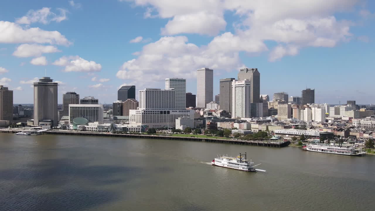 New Orleans, Louisiana skyline seen in a drone timelapse over the Mississippi River on a beautiful day with moving clouds and blue sky