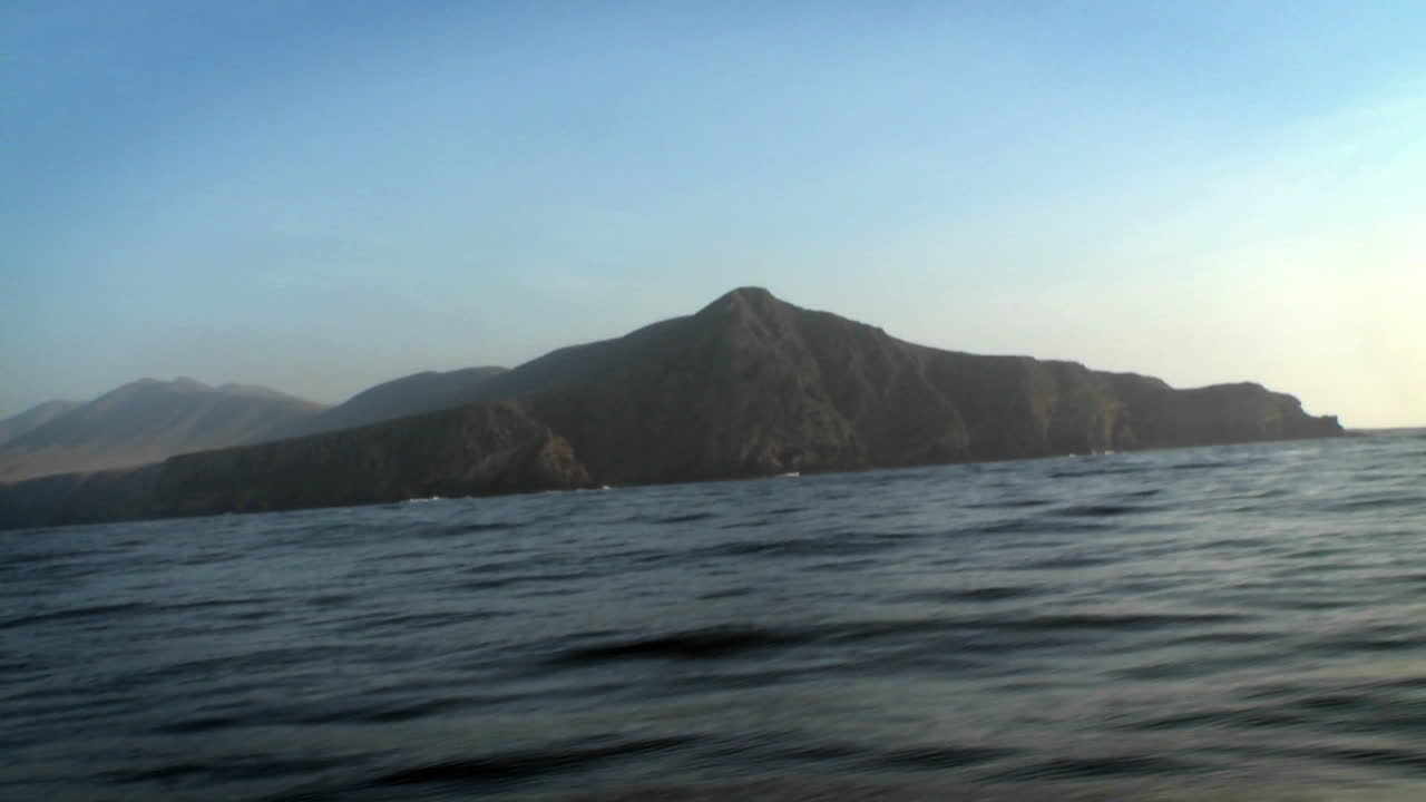 лодка проплывает по воде с другими лодками и горами вдали