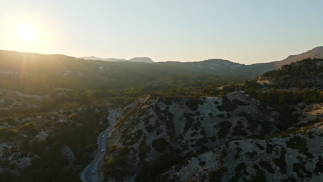 aerial view of the golden hour sun and traffic in middle of mountains in greece