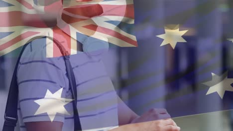 animation of flag of australia waving over man wearing face mask during covid 19 pandemic