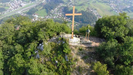 unrecognizable hikers take a break under the gigantic wooden cross of a mountain peak in the clearing of a forest