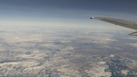 aerial view of snow capped mountains out of from flying airplane window shot in 4k high resolution