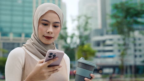 woman in hijab using mobile phone in the city