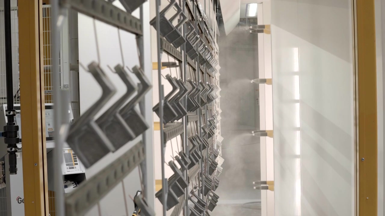 Metal components being powder coated inside an automated industrial painting facility.
