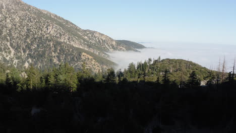 Aerial-View-Above-Sea-of-Clouds,-Temperate-Mountain-Range,-Flying-Down-Into-Shadow